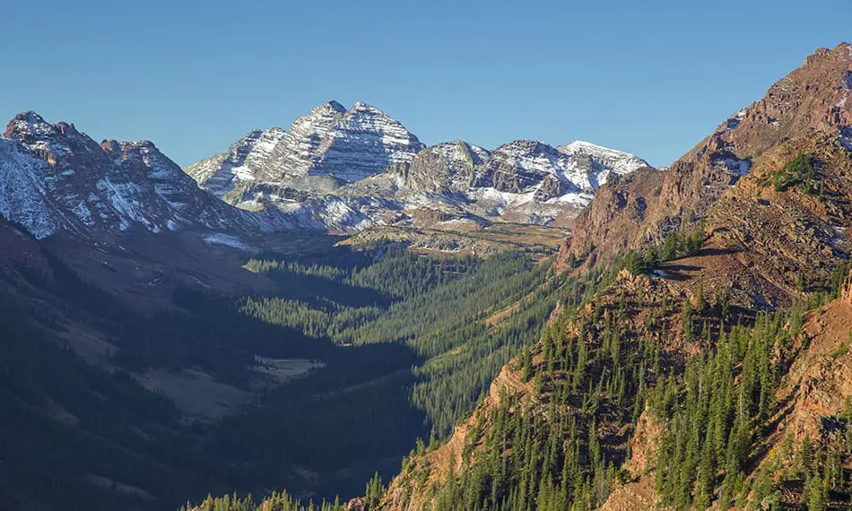 Maroon Bells mountain range behind fall colored hills
