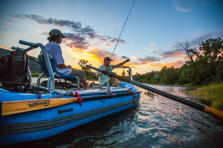 Two men river rafting and fly fishing