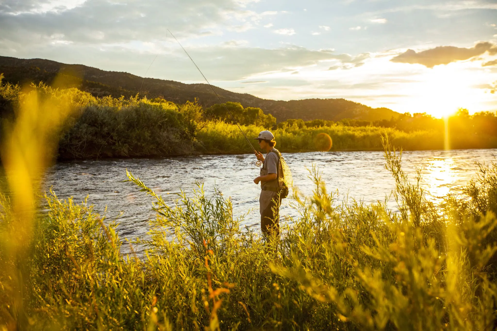 Man on bank of river casting a fly rod
