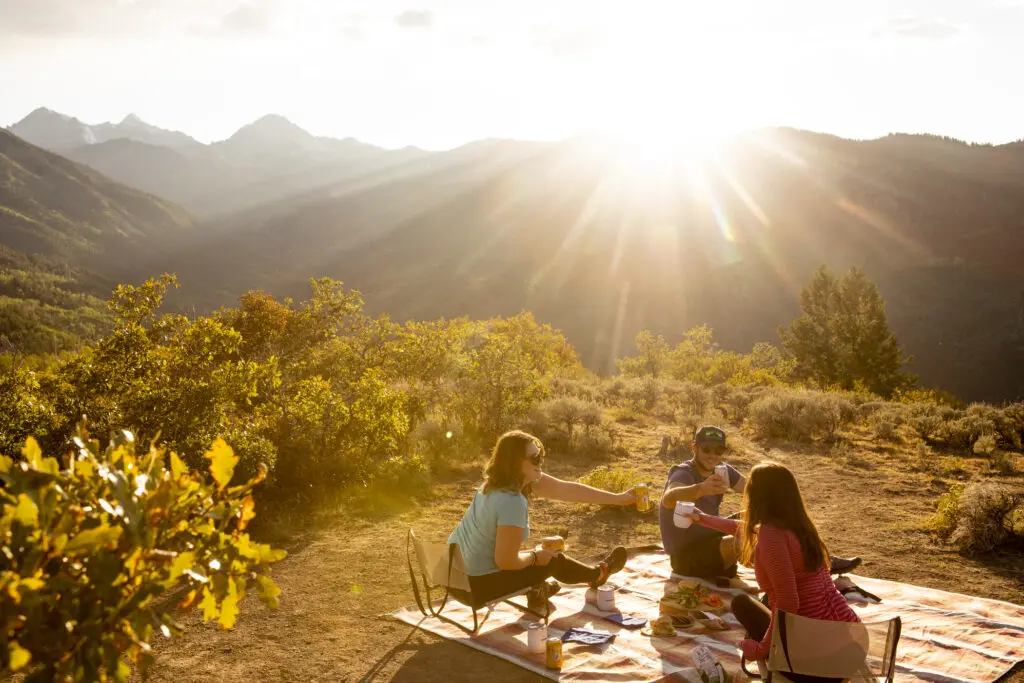 Snowmass sunset picnic at Spiral Point with three young people toasting with a beverage.