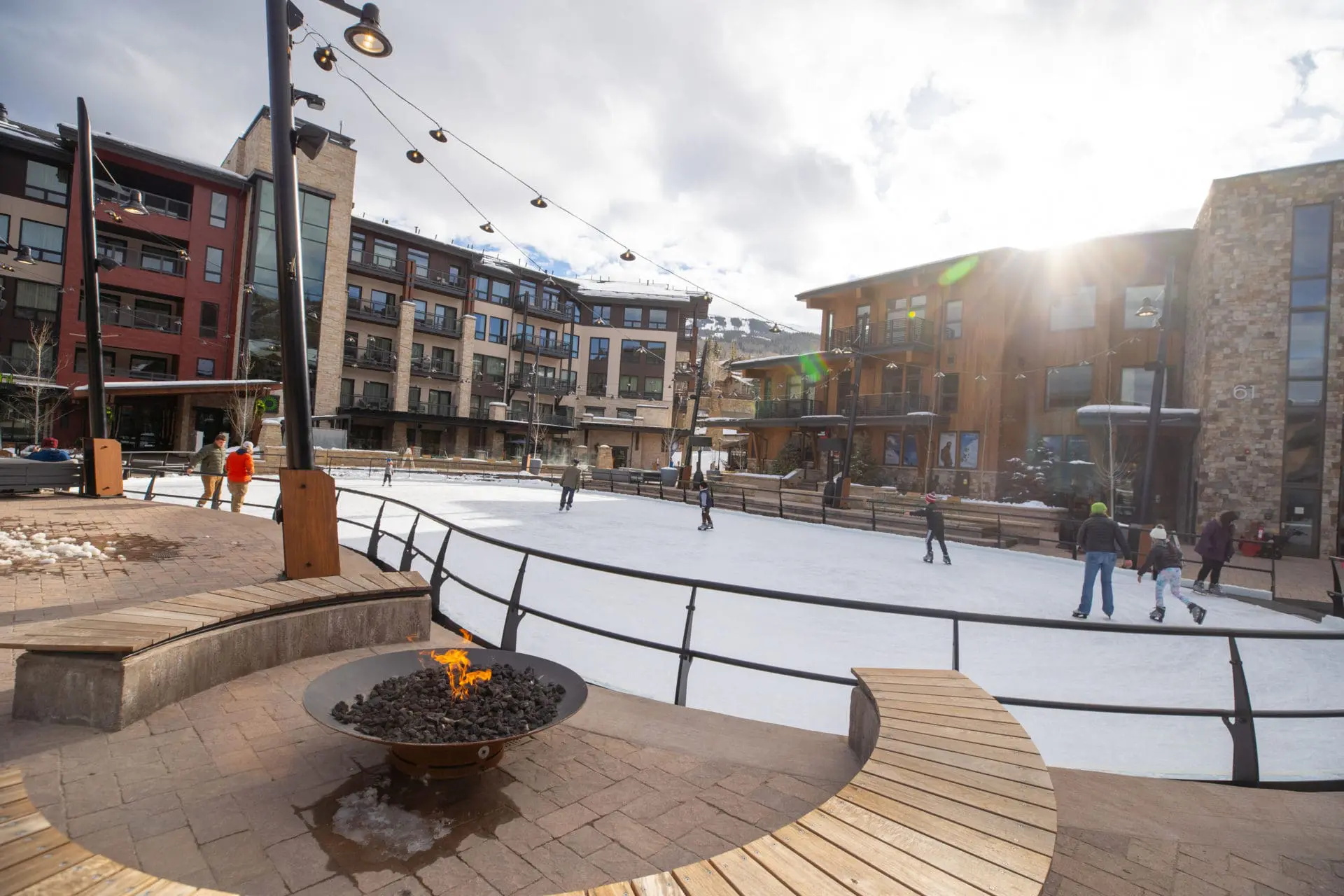 Fire pit next to ice rink, people ice skating