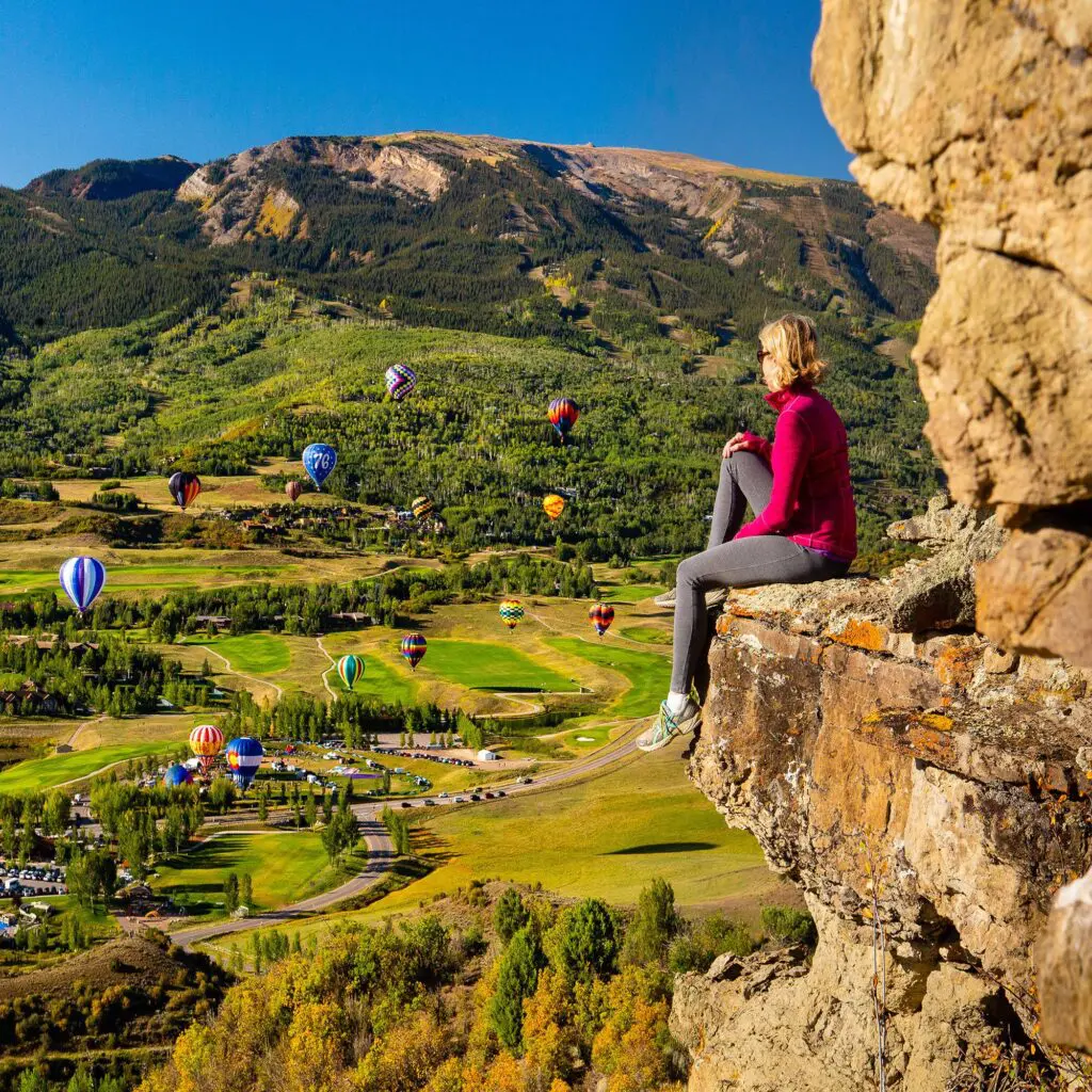 woman watching balloons from a cliff