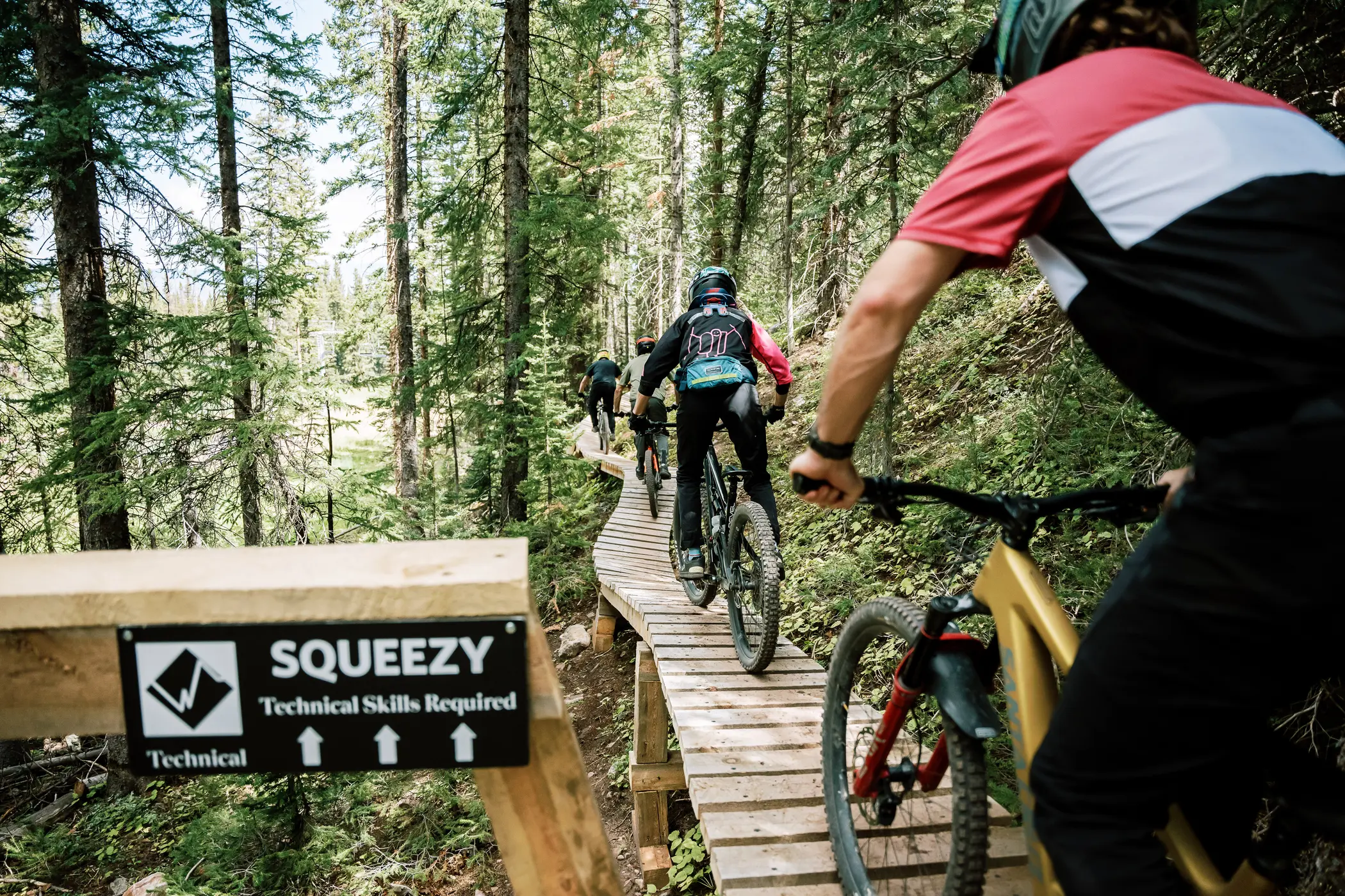 Three mountain bikers from Snowmass 50 on Squeezy, a Snowmass mountain bike trail.
