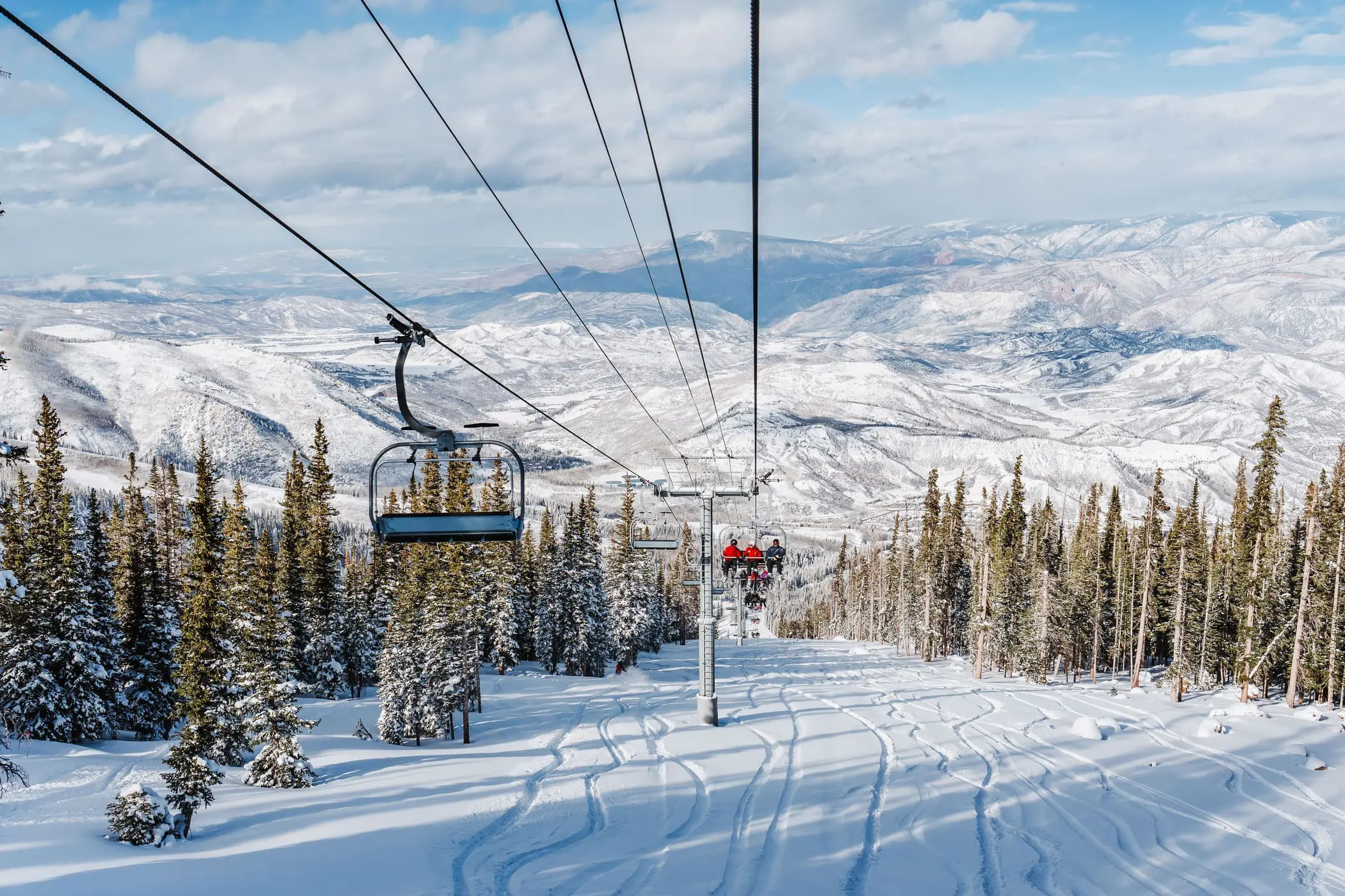 first time skiers in a chairlift going up the mountain while learning how to ski