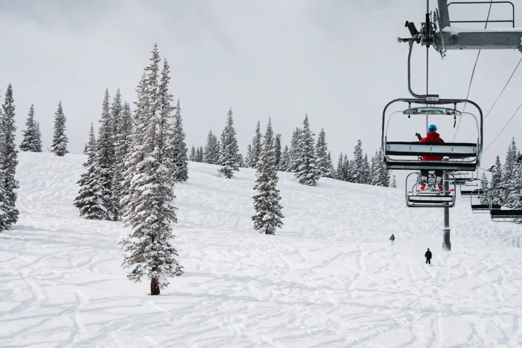 A skier sits on the Big Burn chairlift above fresh snow at Snowmass Ski Area.