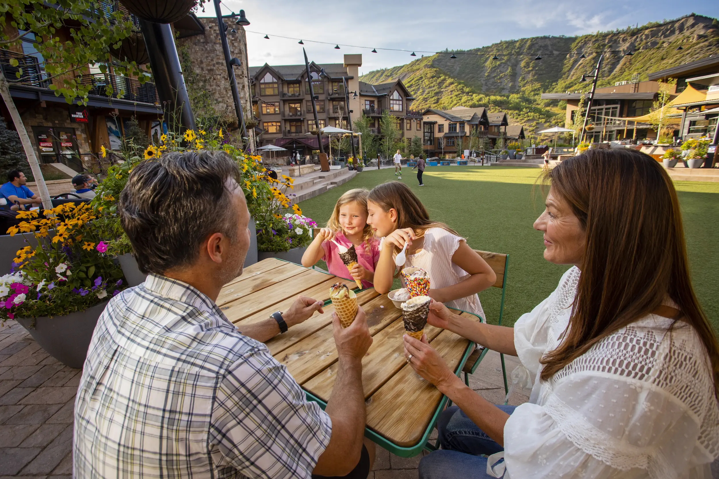 family of four sitting at a table while on their Colorado family vacation and eating ice cream together