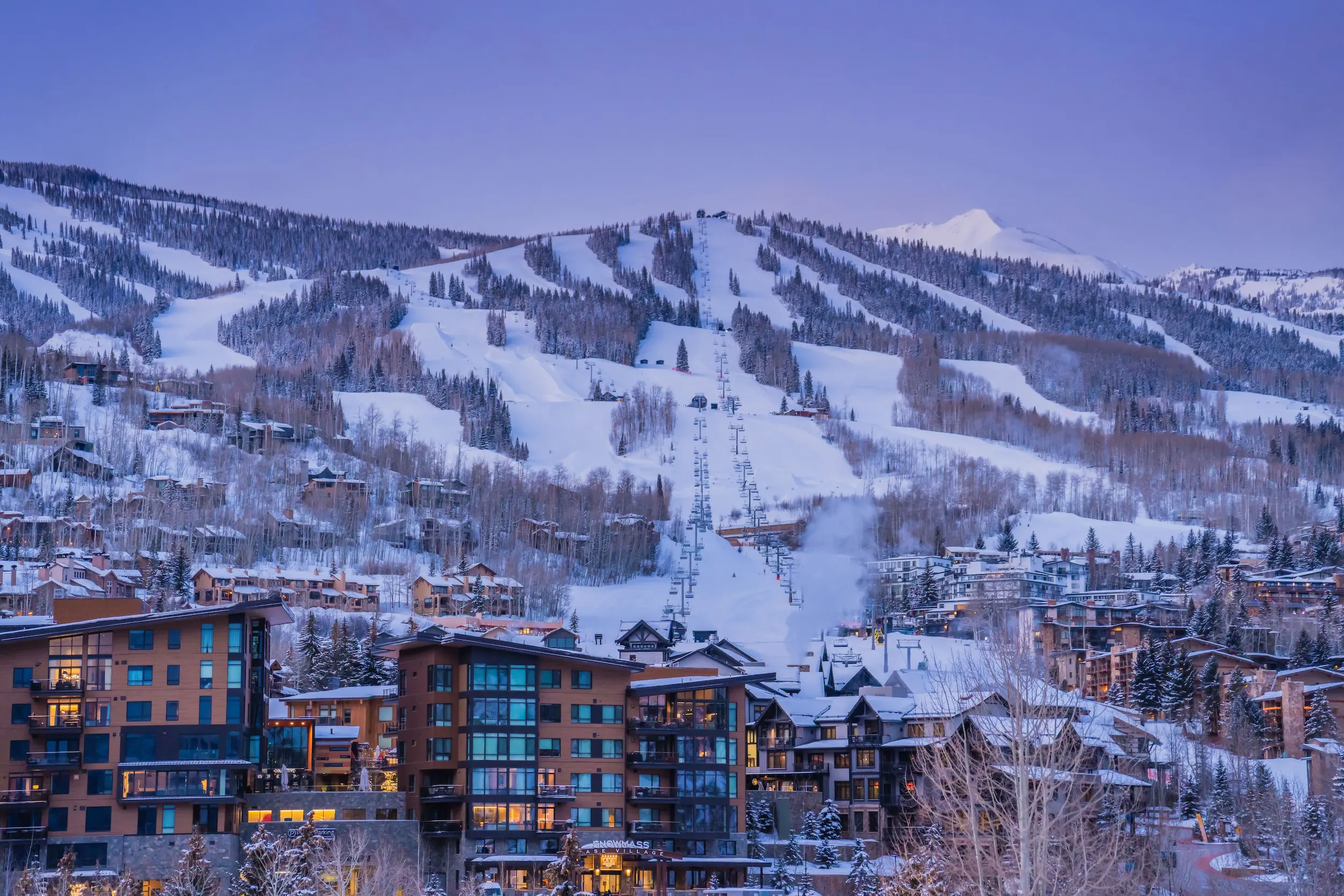 blue hour view of Snowmass ski-in ski-out lodging on a winter day with the sky a shade of purple