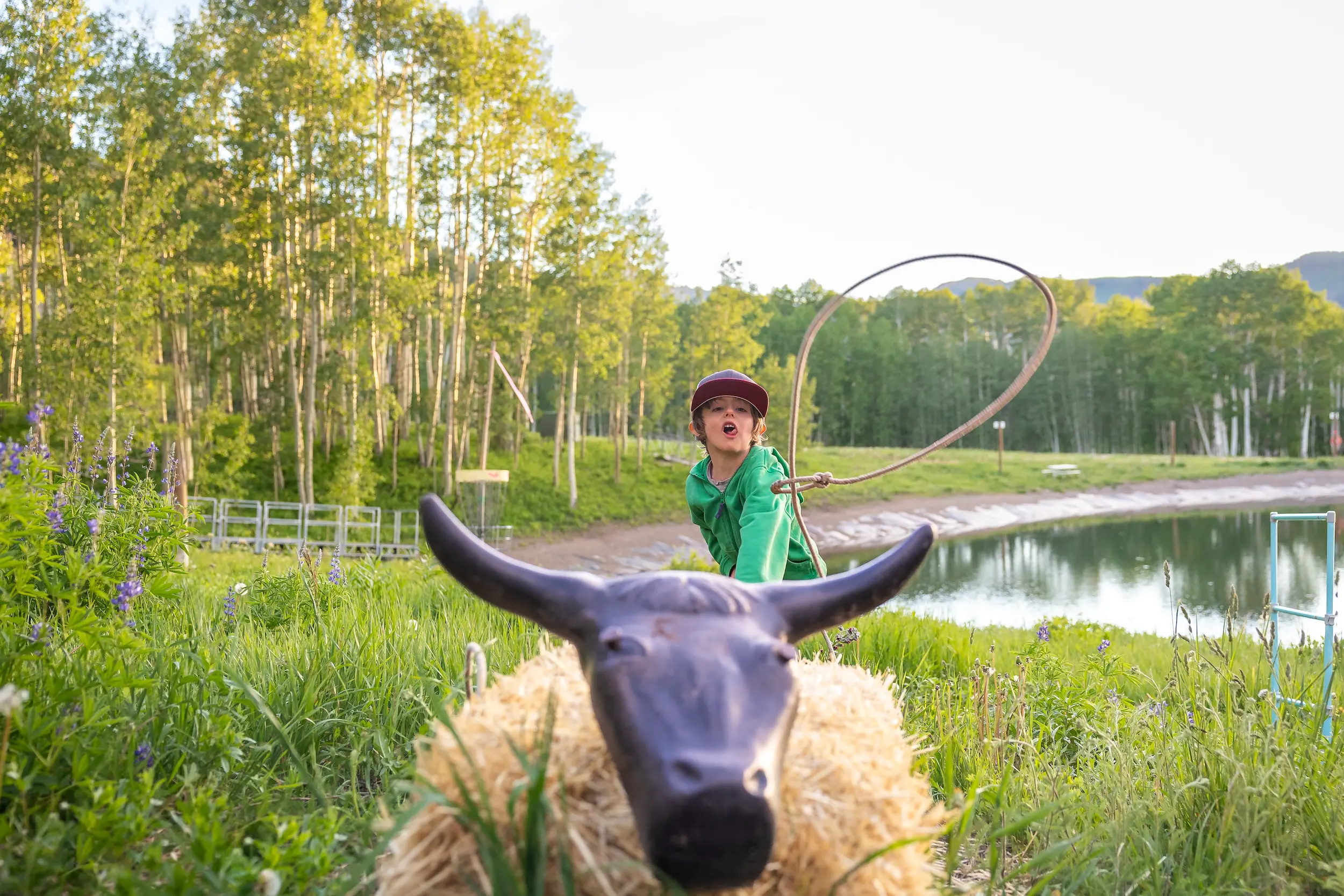 child waving a lasso over a bull statue
