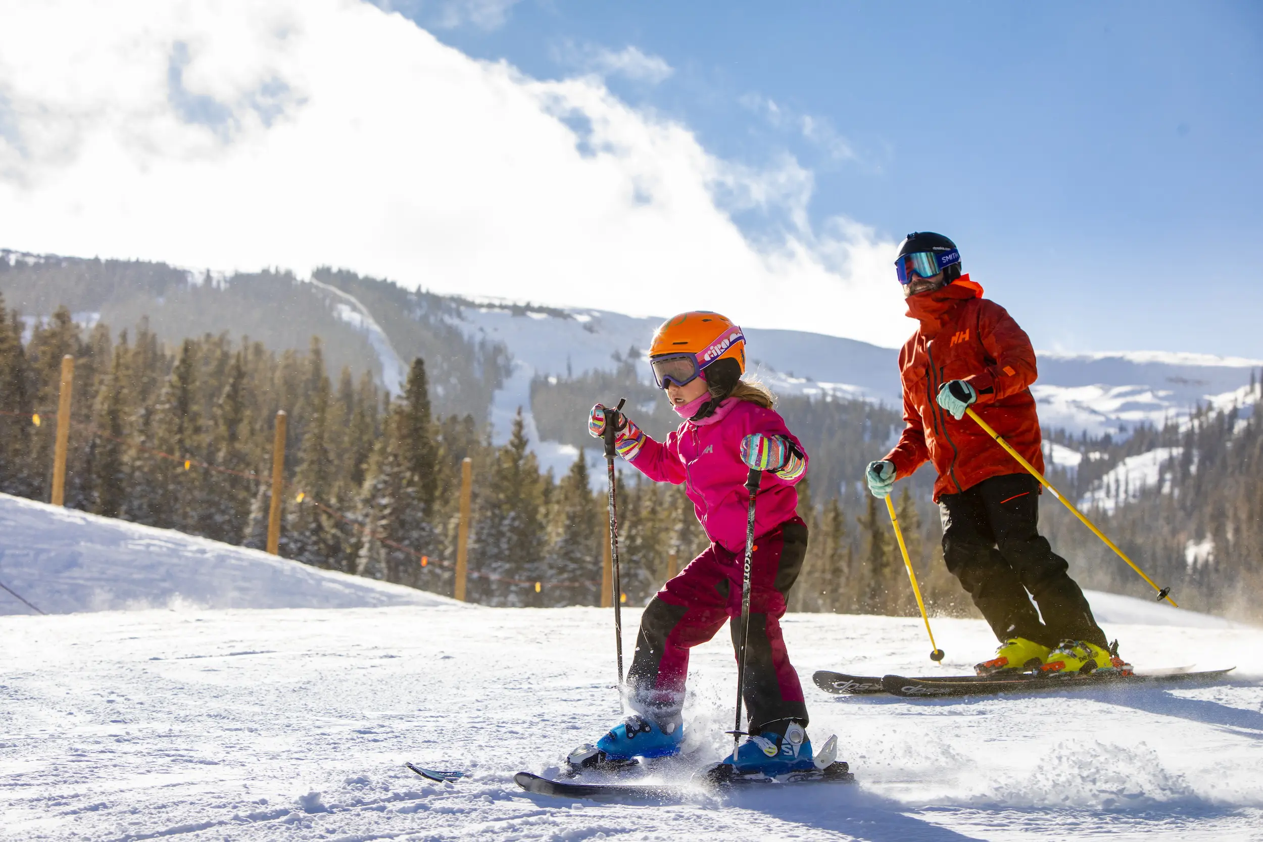little girl skiing in front of her dad