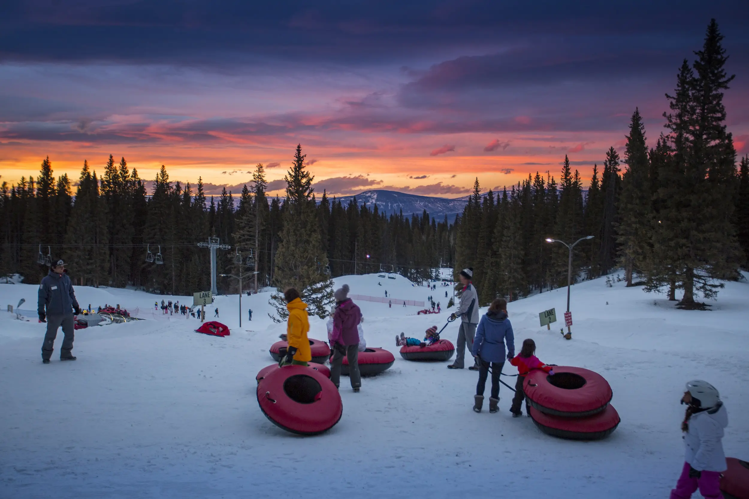 family snow tubing at sunset on their Colorado family vacation