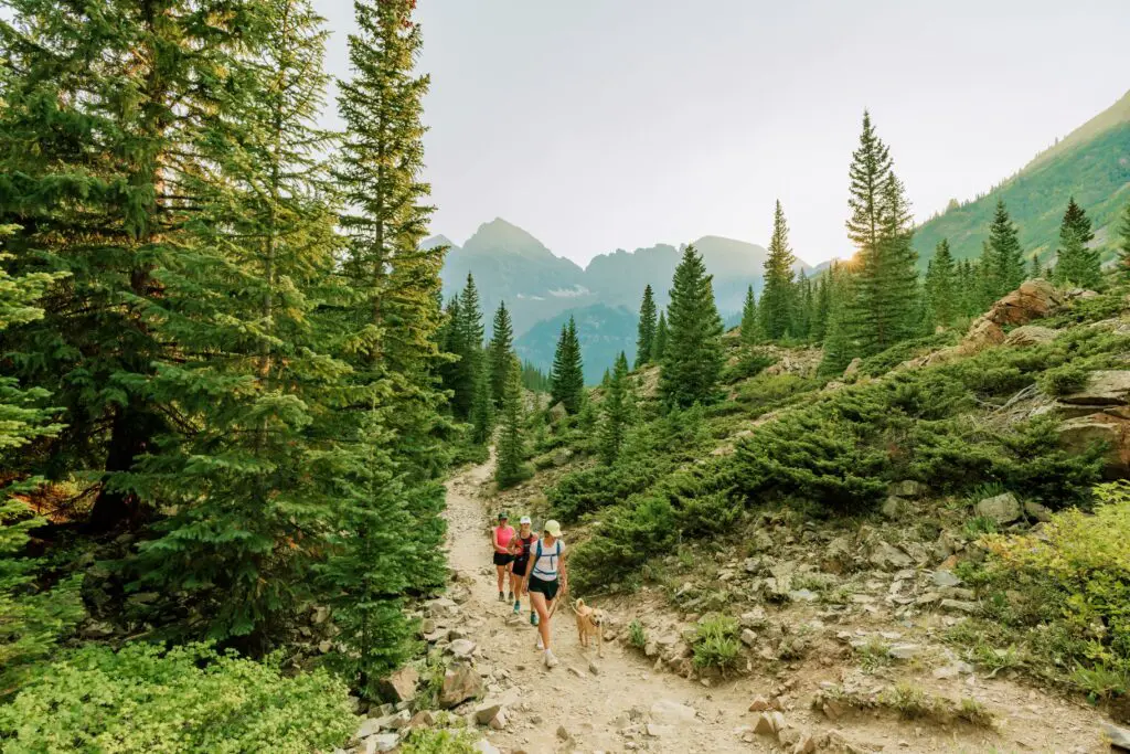 two women hike with their dog near aspen colorado on a summer weekend getaway