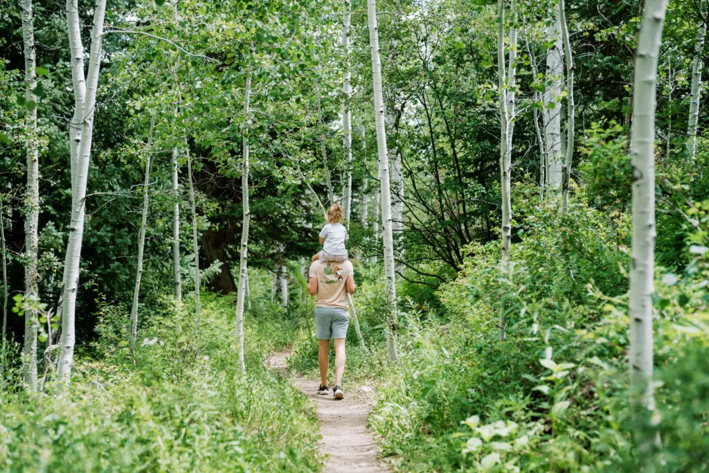 dad on a lush hiking trail in snowmass with toddler on his shoulders