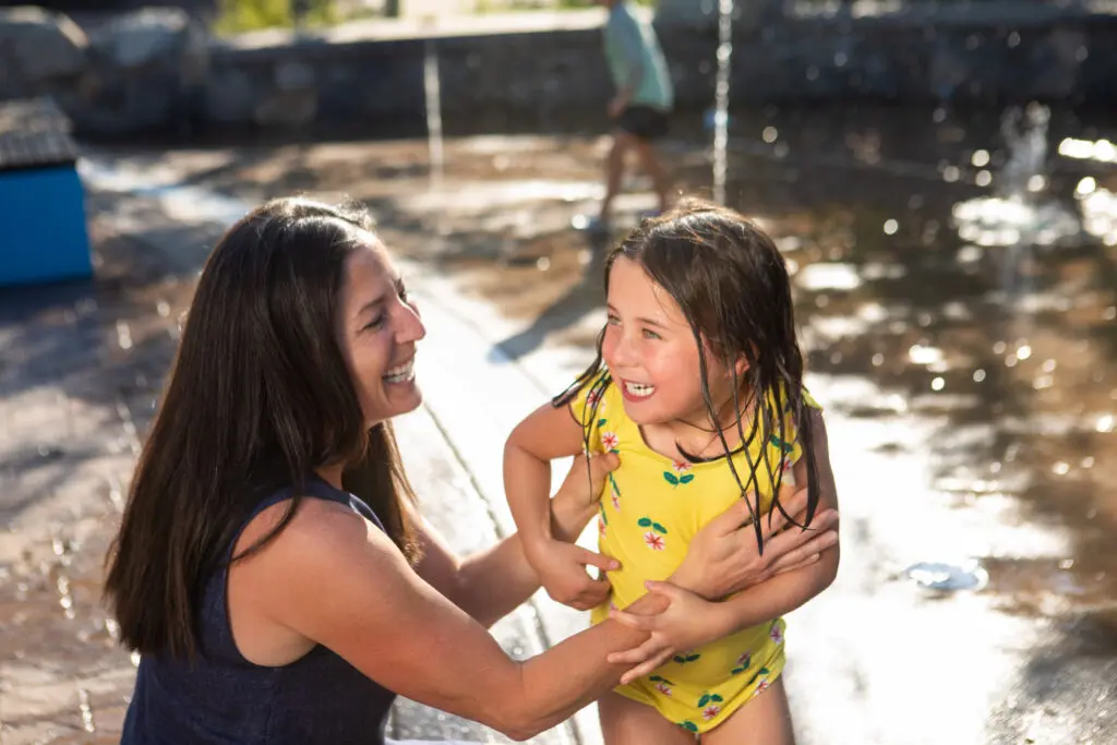 parent visiting snowmass with toddler at the splash pad in base village