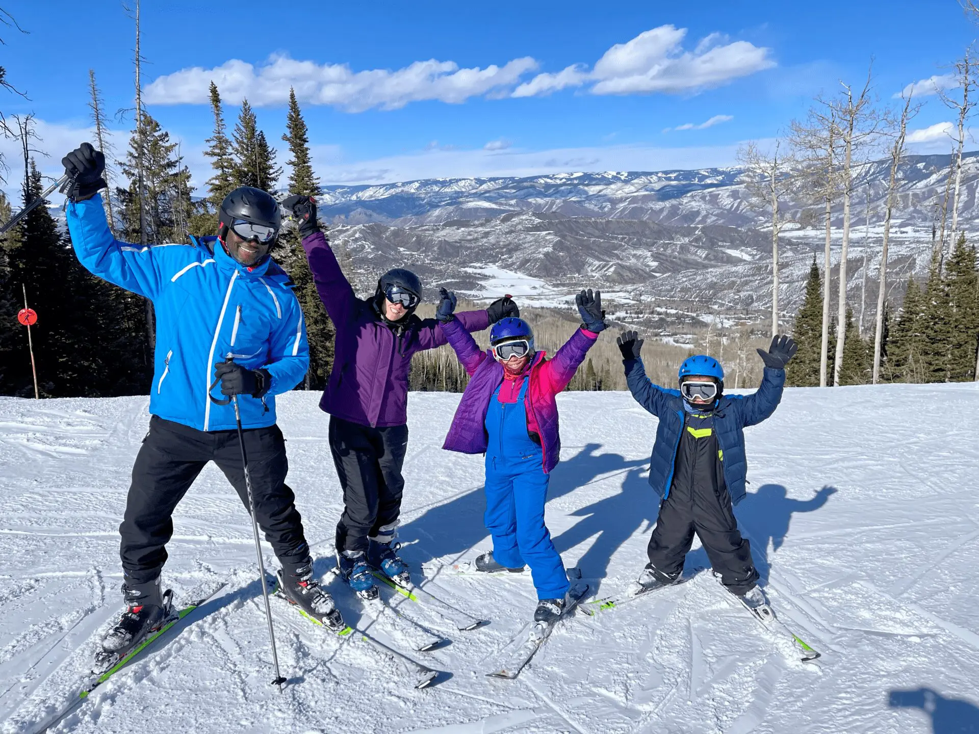 family of first time skiers throwing their hands up in the air in excitement